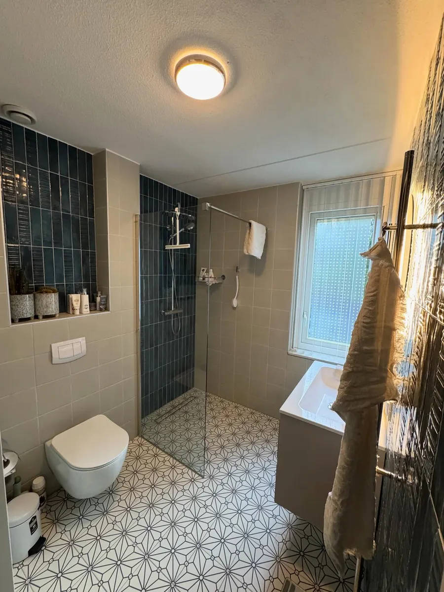 Opgeleverde badkamer met blauwe wandtegels en inloopdouche