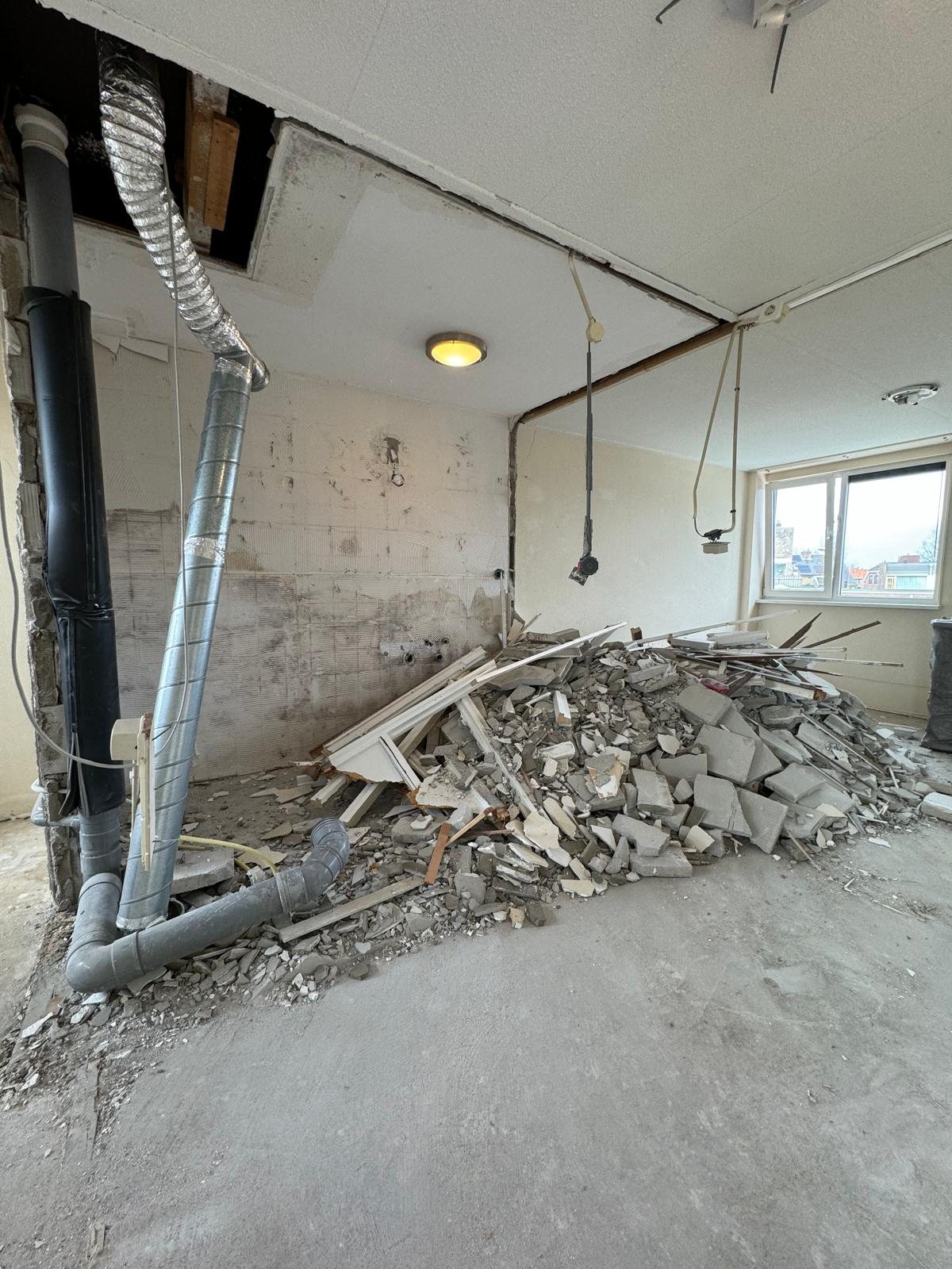 Gestripte kamer met leidingen en puin