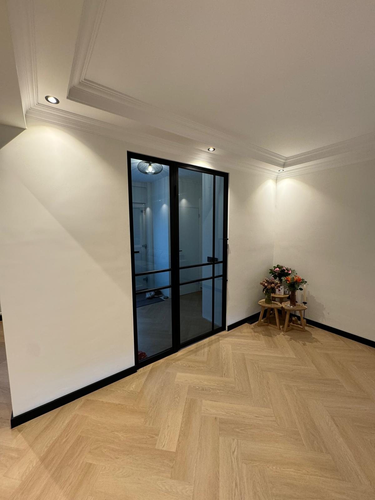 Stalen deuren met glas in een witte wand, visgraatvloer