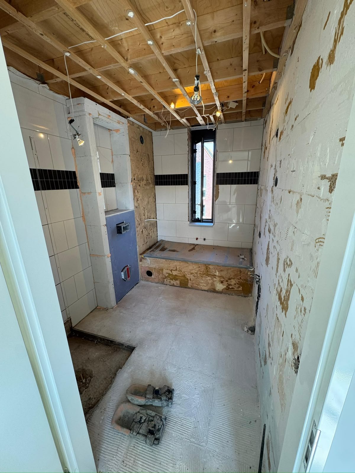 Tijdens: gestripte badkamer met open plafond en leidingwerk