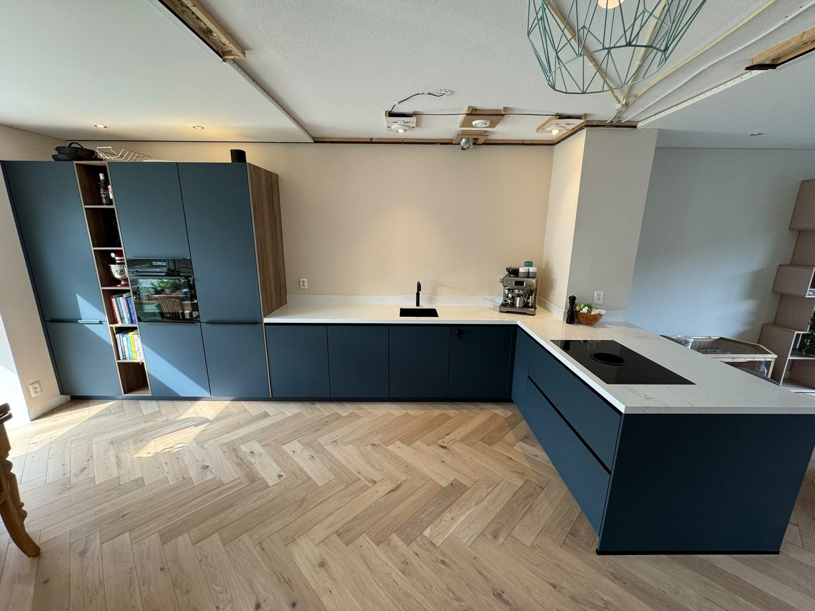 Overzicht van de keuken met hoge kasten en open plafondstroken