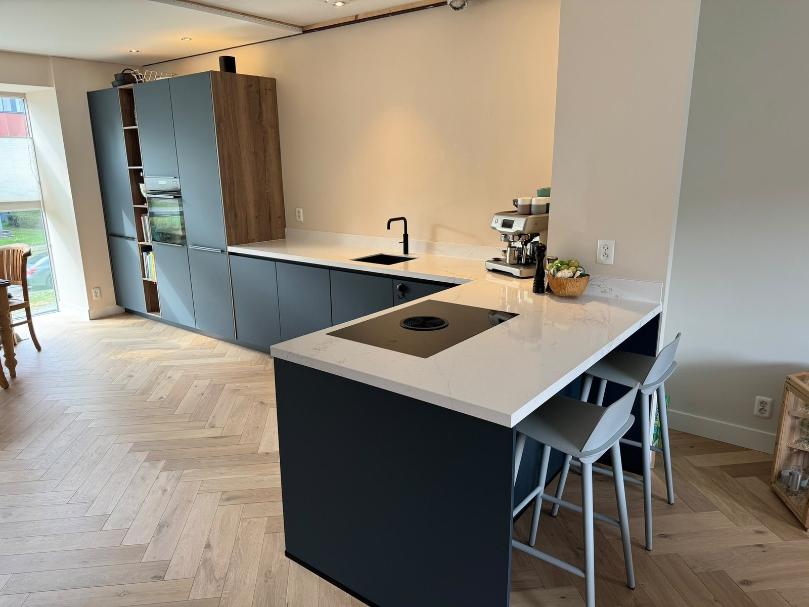 Keuken in Utrecht met donkerblauwe kasten, licht blad en visgraatvloer